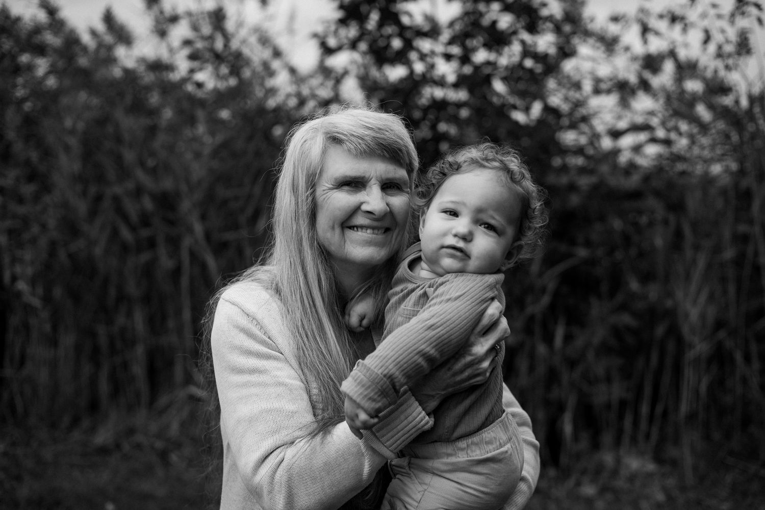A series of black and white photos showing joyful moments between two people laughing and embracing outdoors.
