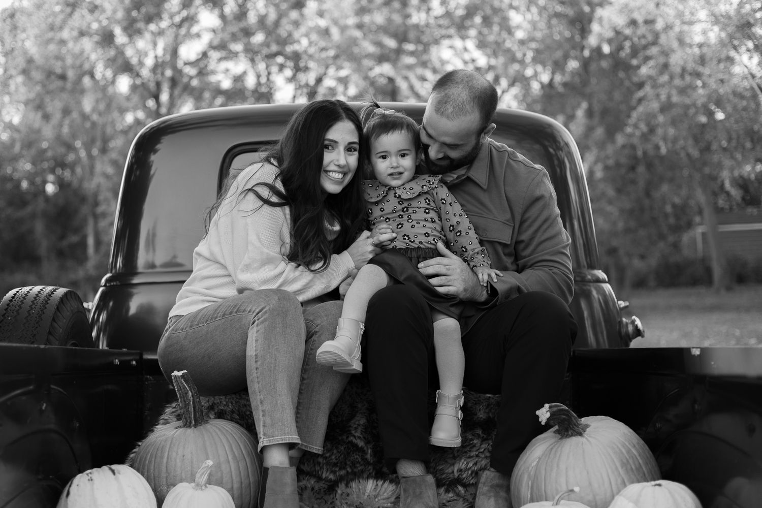 A collection of black and white photos showing tender family moments between parents and child outdoors.