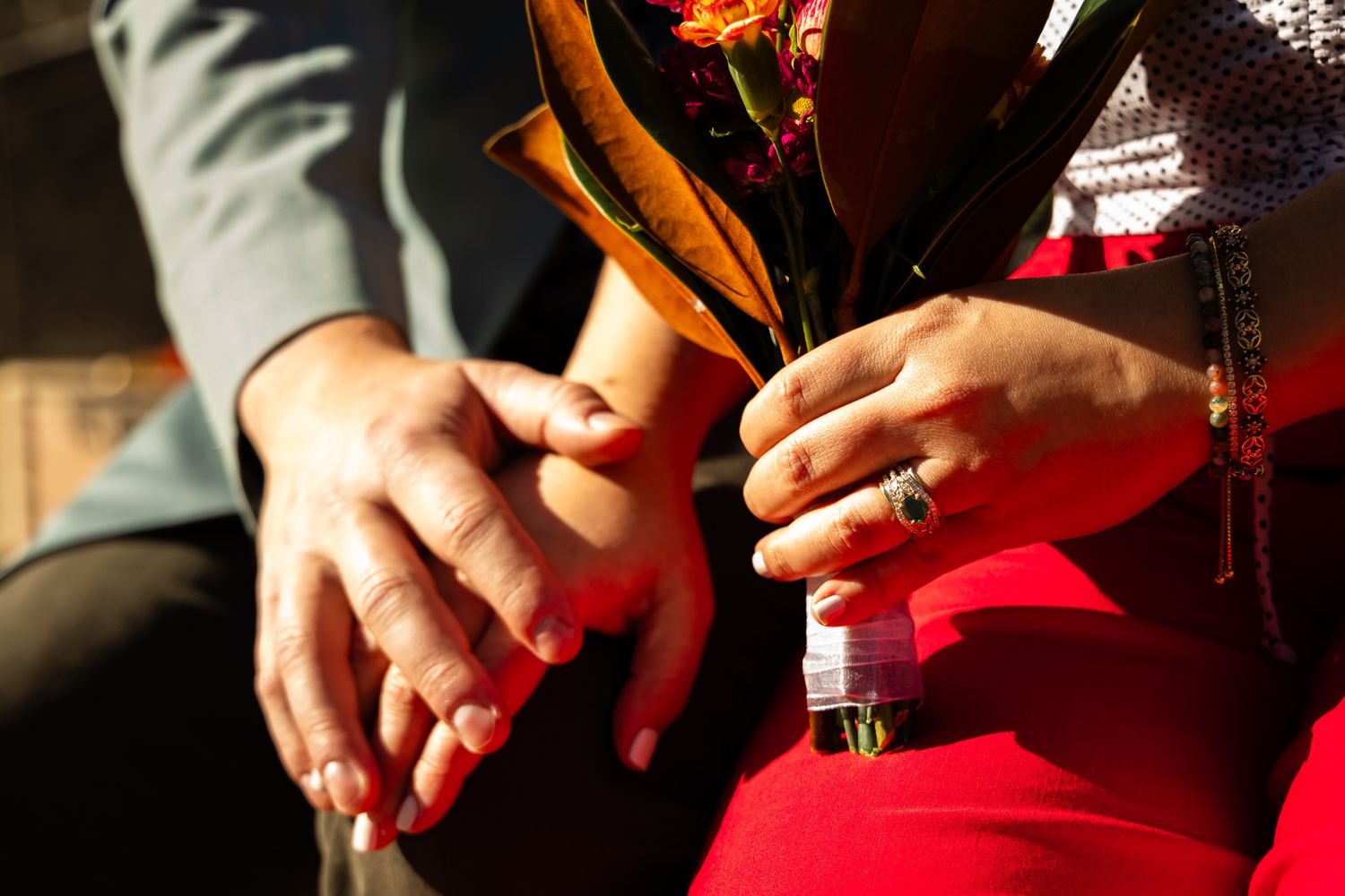 Close-up shot of hands rolling a red fabric material on a wooden surface in warm lighting.