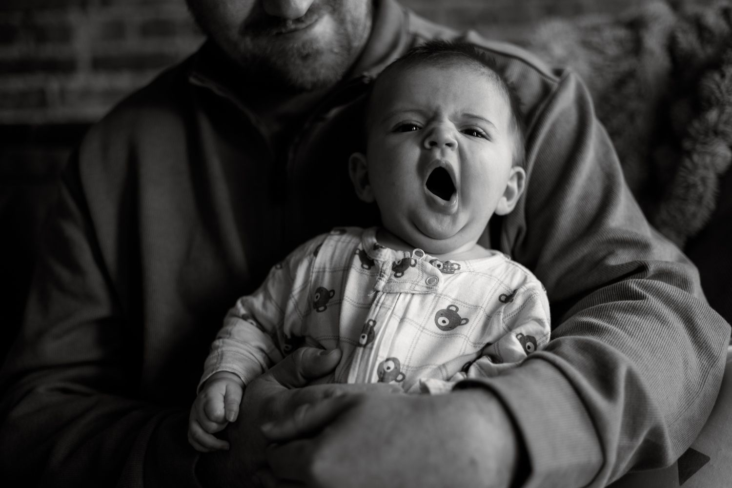 A series of black and white photos showing a baby's expressions progressing from smiling to laughing and yawning.