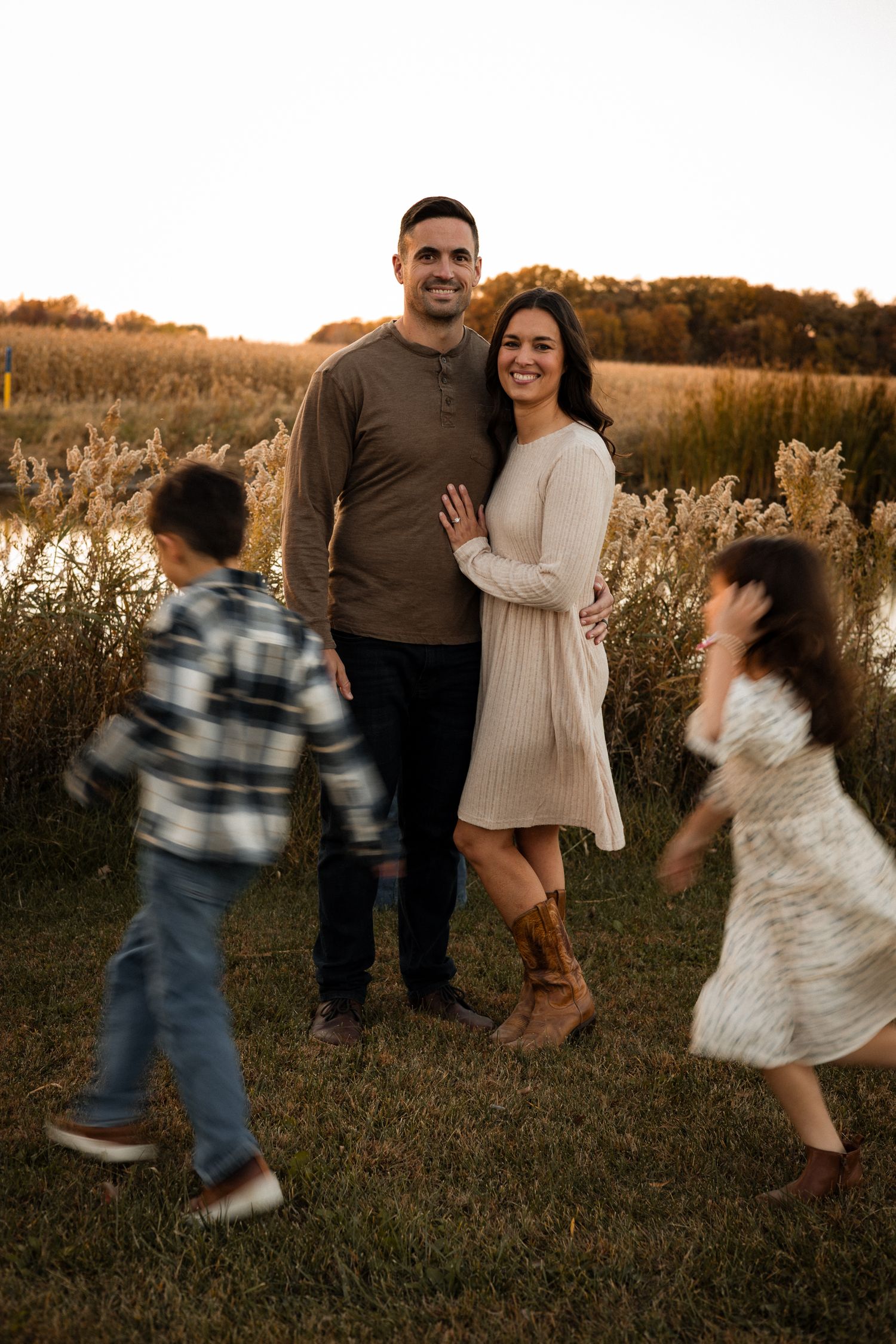 Family portrait in autumn field with children playing in motion.