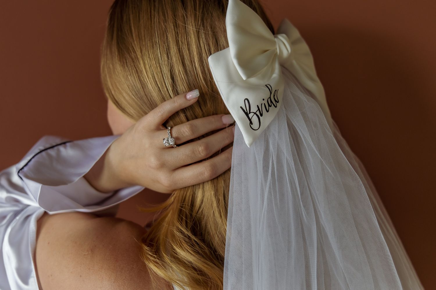 Detail shot of bridal veil with 'Bride' text and blonde hair.