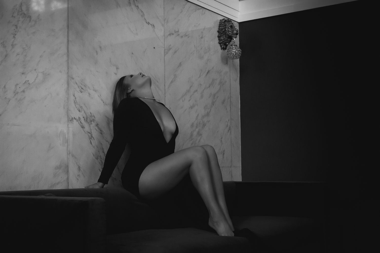 Artistic boudoir photo in black and white against marble wall.