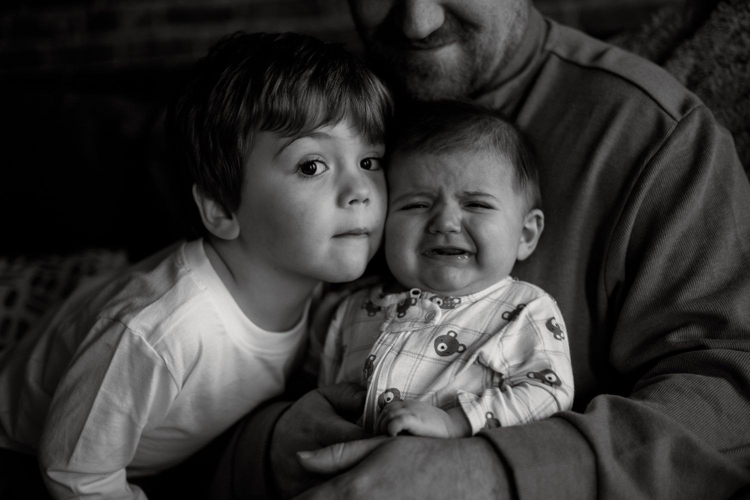 Black and white intimate portrait showing tender emotional moment between two people.