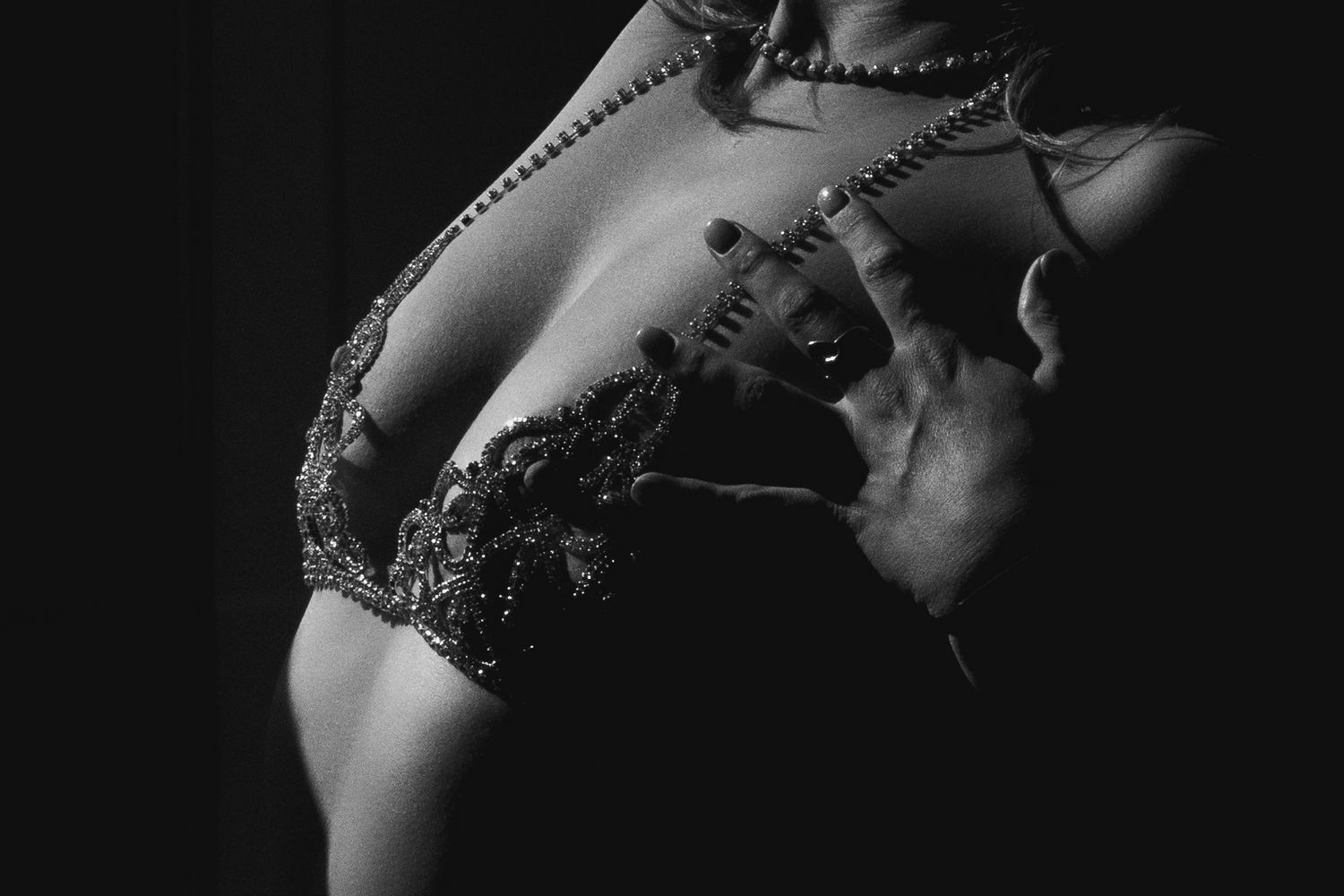 Black and white artistic boudoir photograph showing a woman's torso in lace lingerie with dramatic side lighting.
