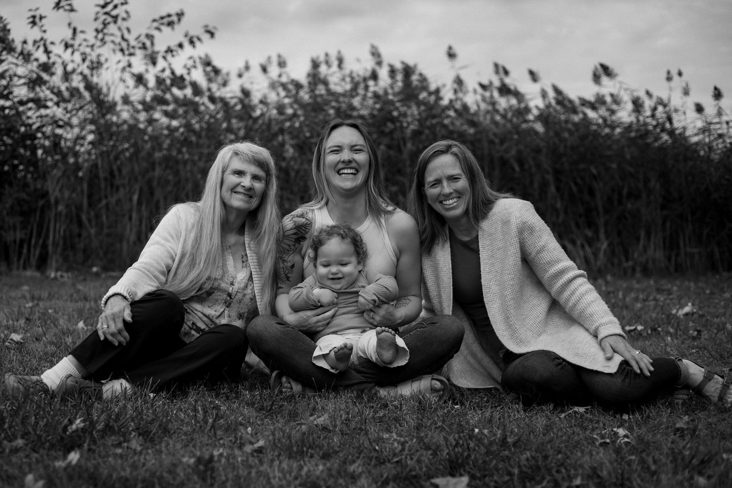 A series of black and white photos showing people lying and laughing together on grass in a candid playful style.