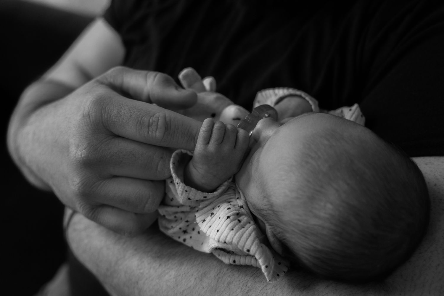 A series of black and white photos showing tender moments between a parent and newborn baby.