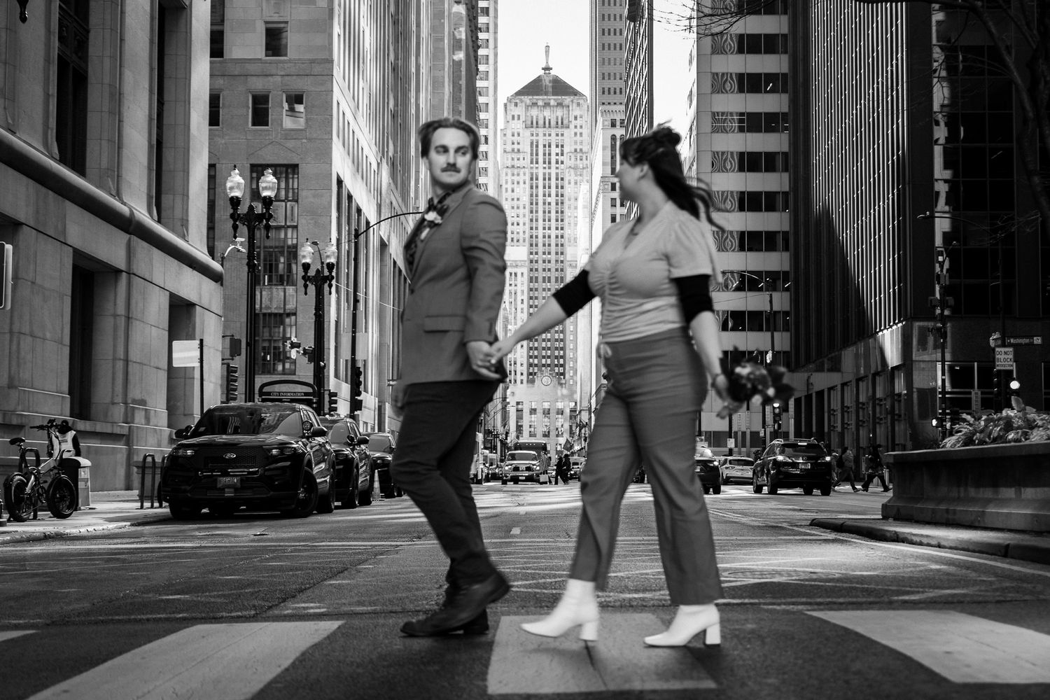 Urban street scene with tall buildings creating dramatic shadows in black and white photography.