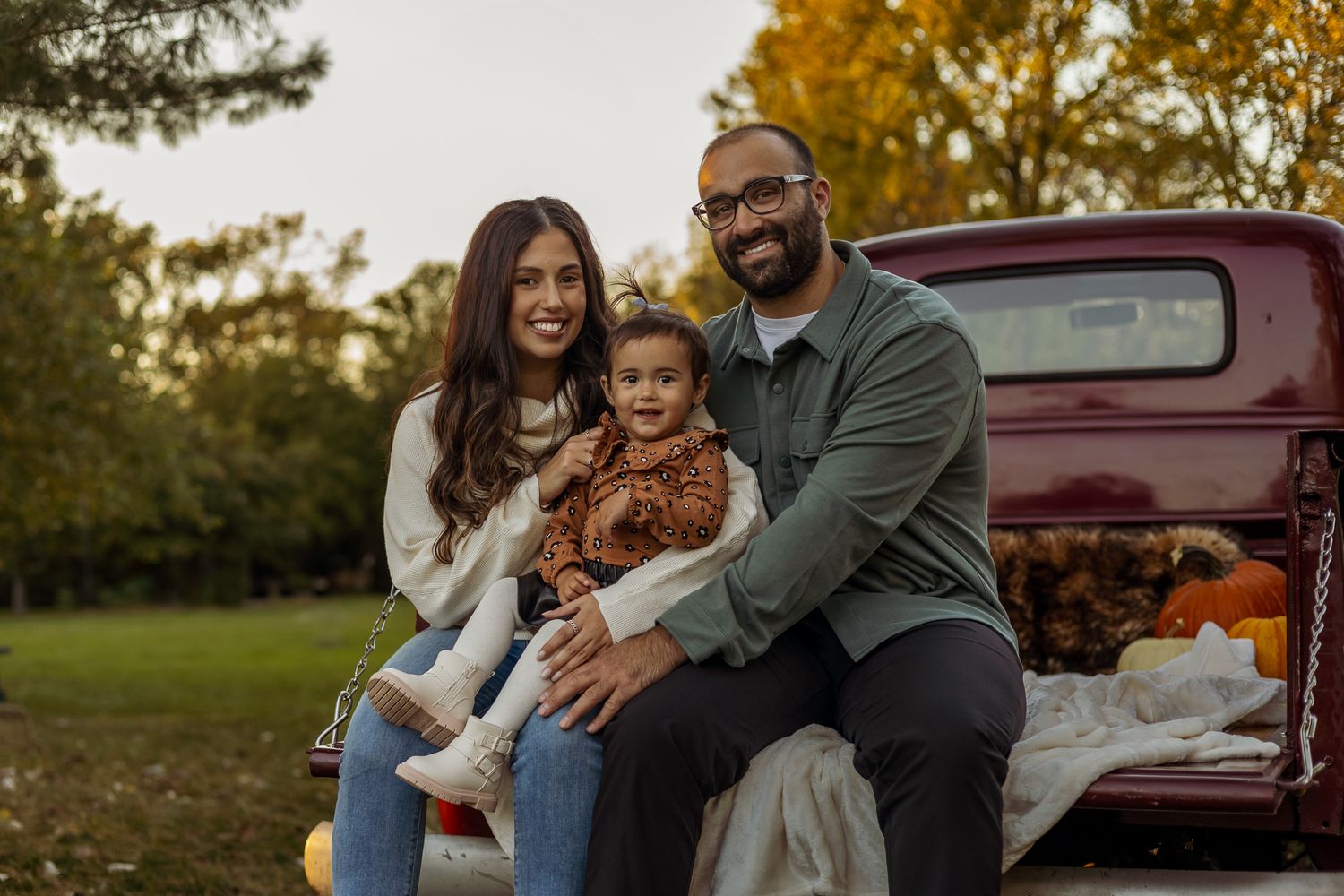 A couple shares intimate moments during a golden hour outdoor photo session with a vintage red car in the background.