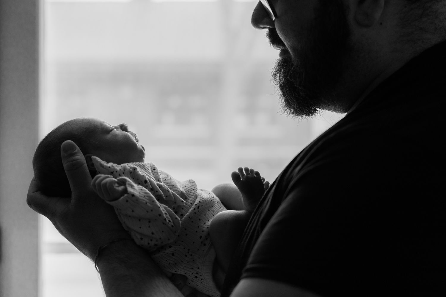 A silhouetted figure is seen in profile against a bright window in this black and white photograph.