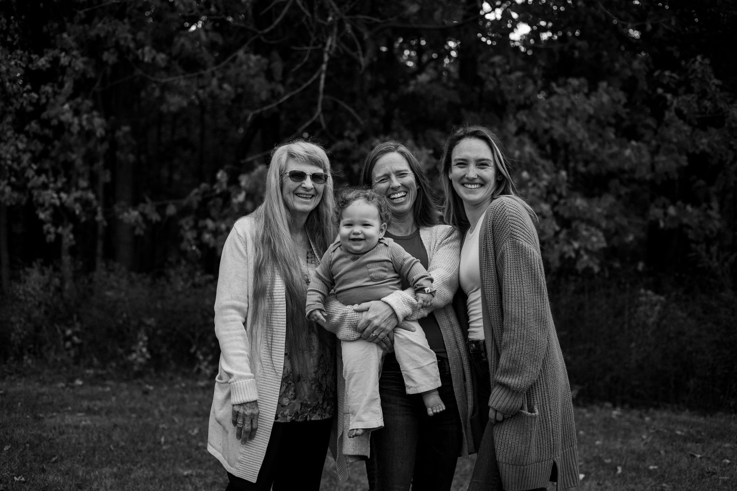 Black and white portrait of a family sharing laughter together in a natural outdoor setting.