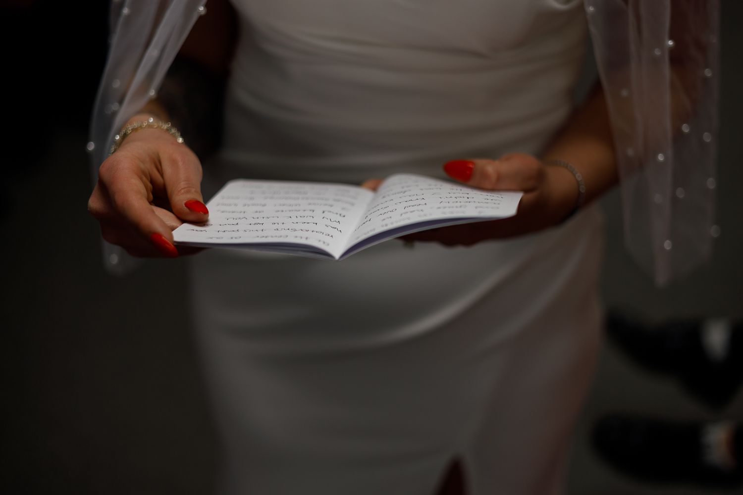 Someone holds an open book while reading against a dark background.