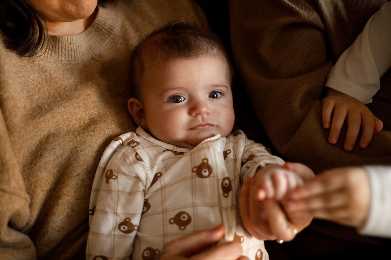 Black and white portrait of a baby being held against a warm textured background.