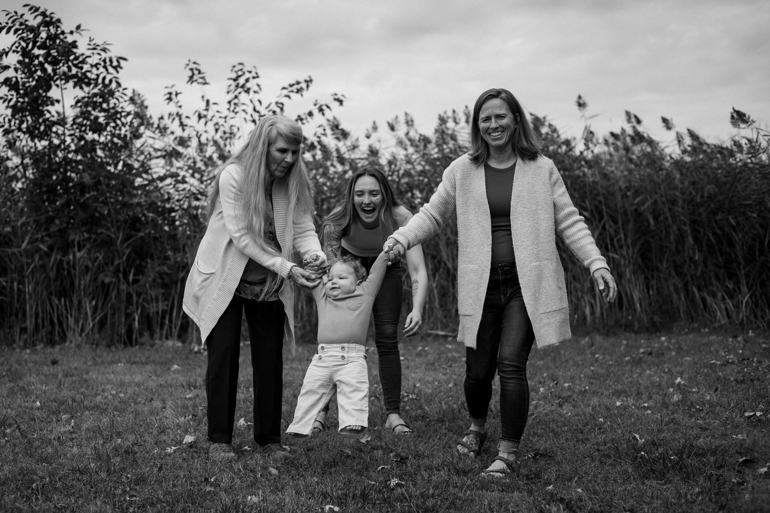 A series of black and white candid photos showing joyful moments between people outdoors in a natural setting.