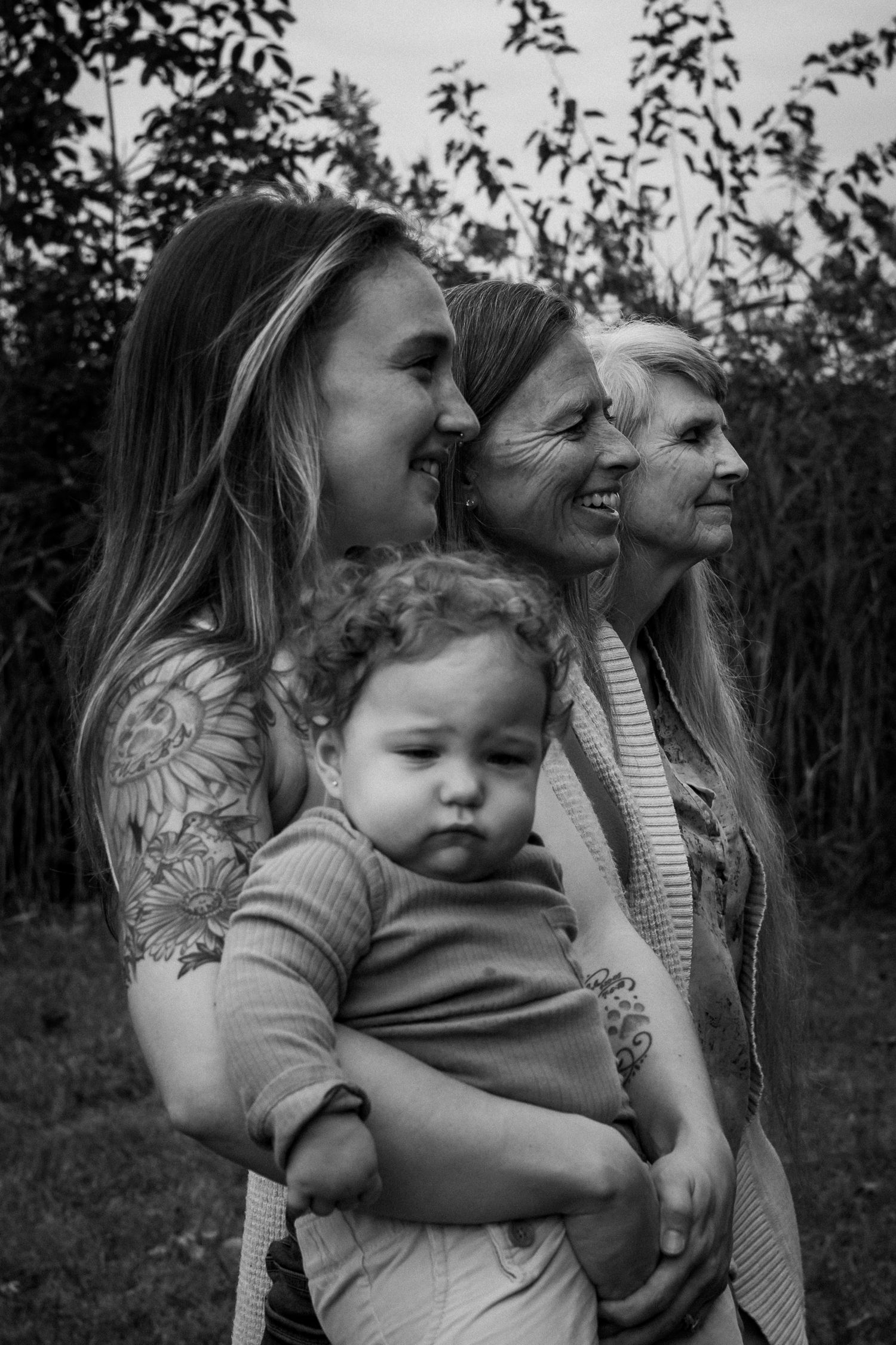 A series of black and white photos showing tender moments between family members embracing outdoors in nature.