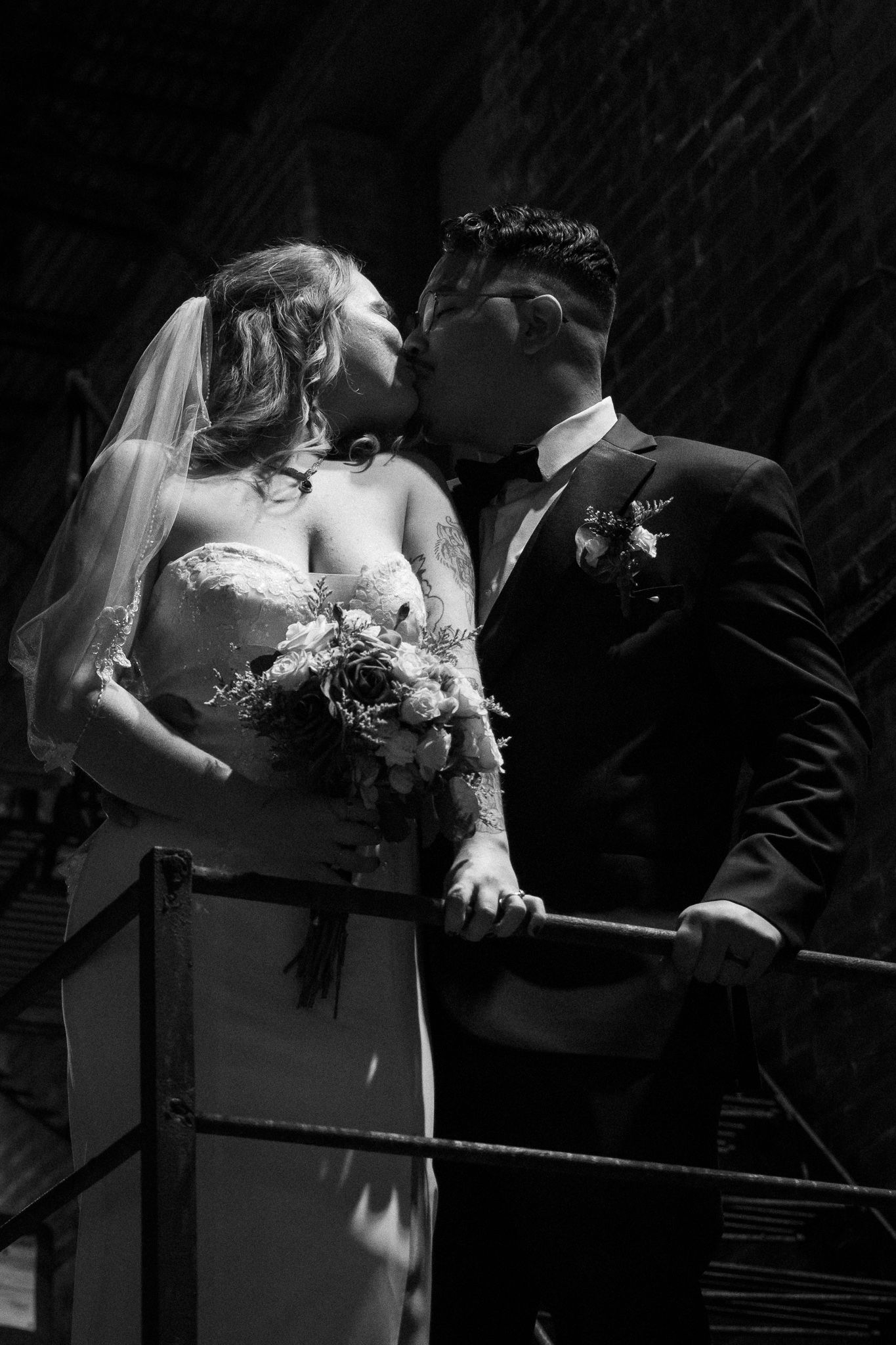 A black and white wedding photo series showing intimate moments between newlyweds leaning over a railing.
