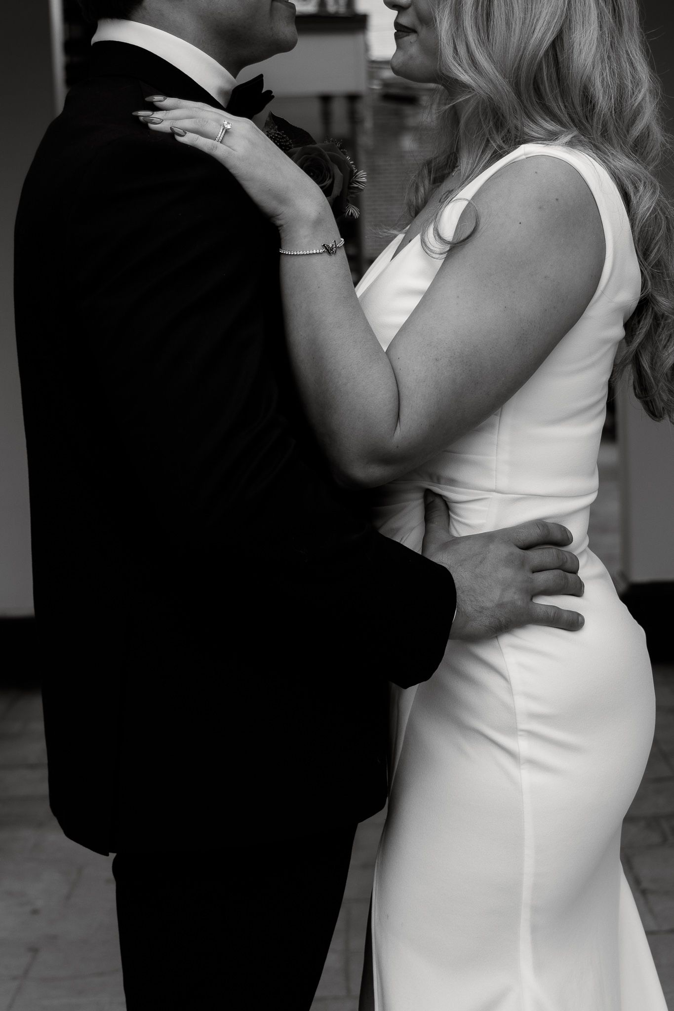 A couple in formal attire dance together, with the woman wearing a white dress and the man in a black suit.