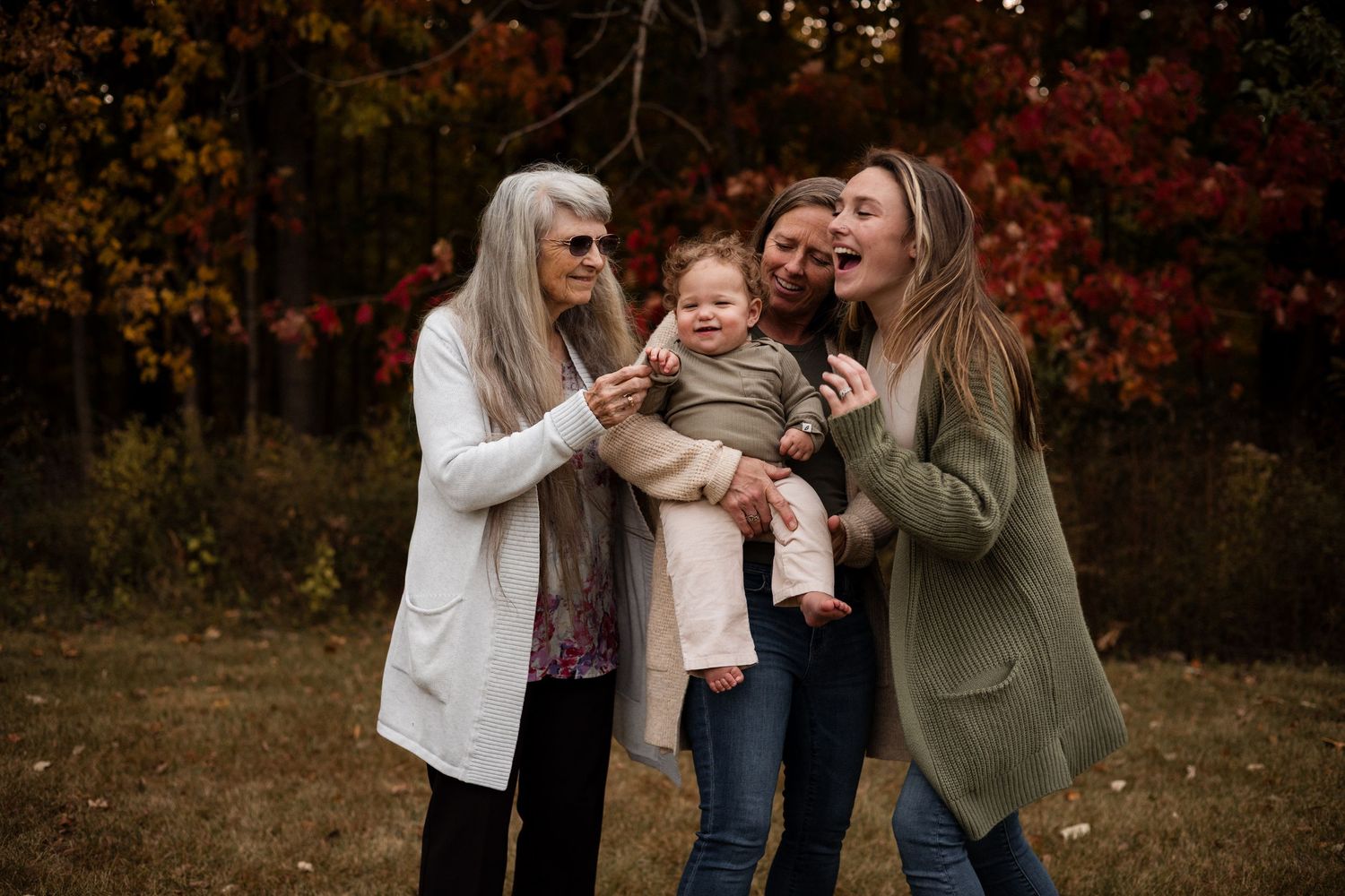A joyful family moment captured outdoors during autumn with fall foliage in the background.