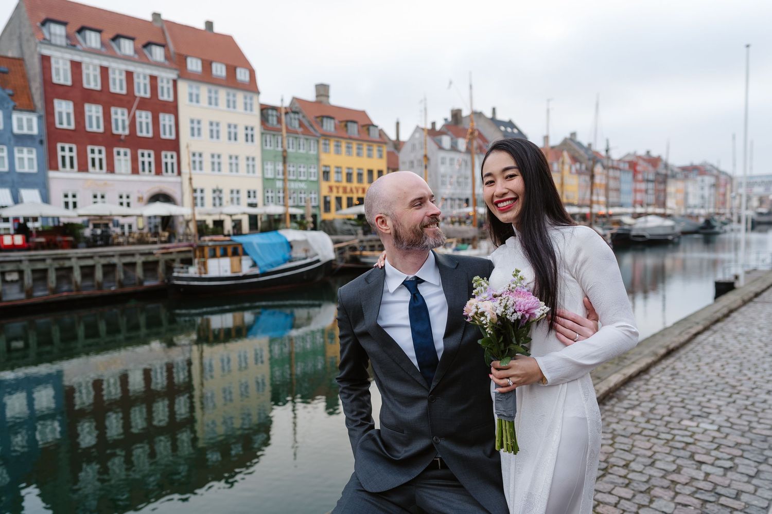 Newlyweds walking along Nyhavn Canal in Copenhagen. Denmark wedding. Scandinavian & Destination Wedding Photographer