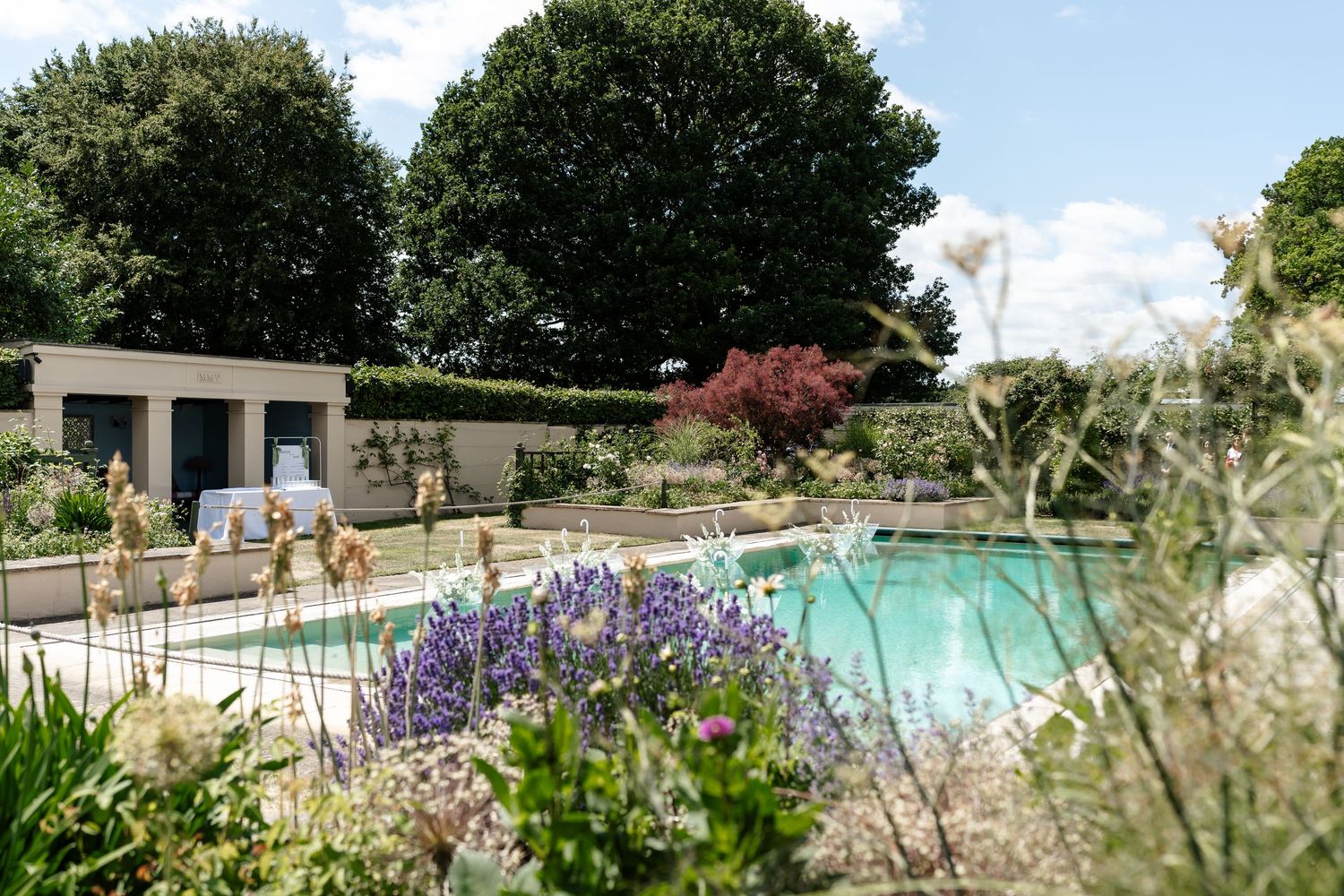 Elegant outdoor wedding venue pool surrounded by lavender and lush garden hedges.