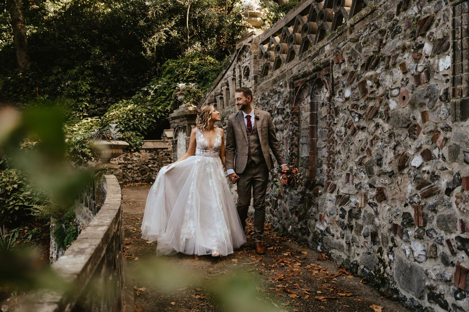 bride and groom walking holding hands along the walled gardens in Norwich, Norfolk. Wedding photographer