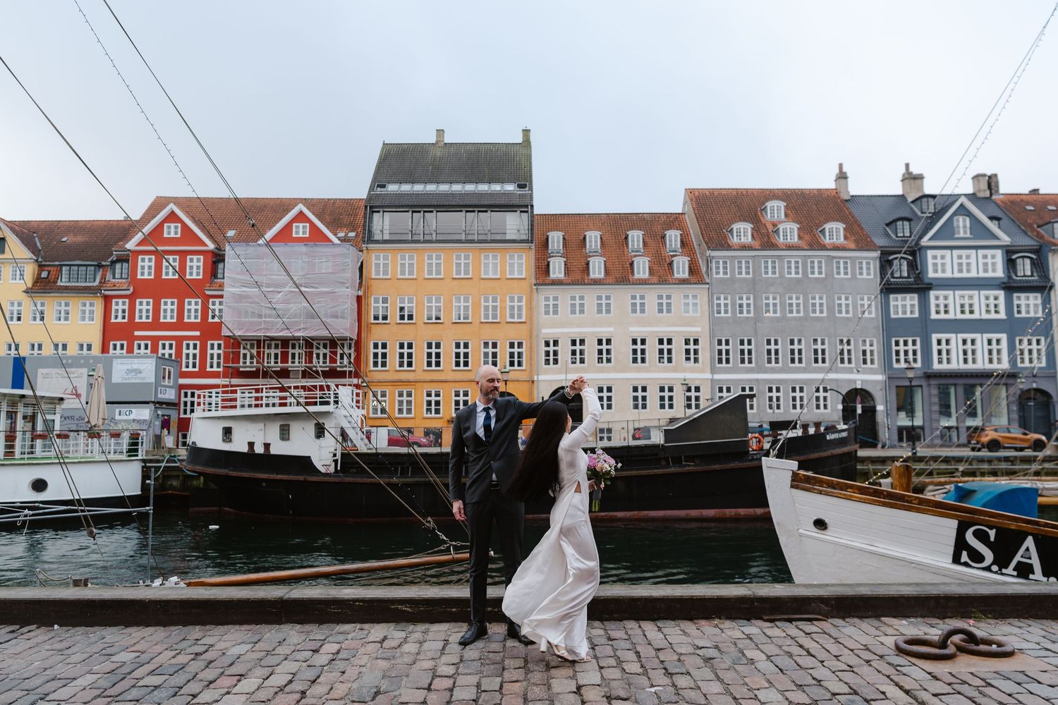 Newlyweds walking along Nyhavn Canal in Copenhagen. Denmark wedding. Scandinavian & Destination Wedding Photographer