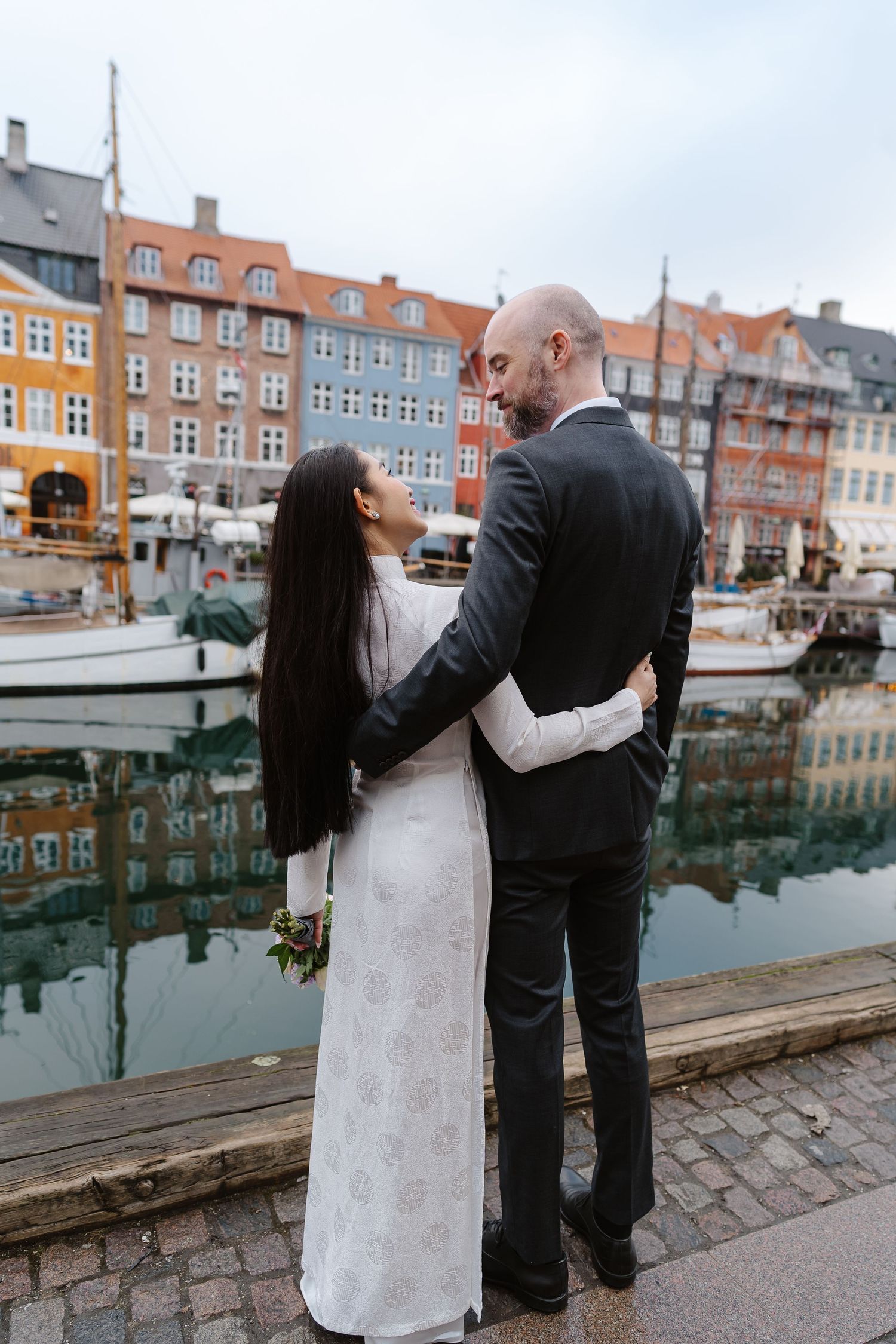 Newlyweds walking along Nyhavn Canal in Copenhagen. Denmark wedding. Scandinavian & Destination Wedding Photographer