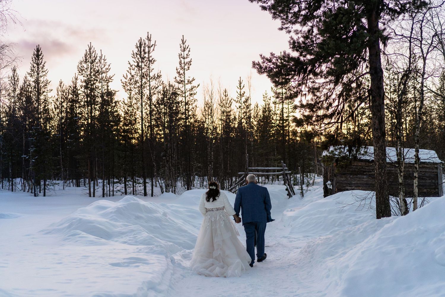Couple candidly walking through forest at Twilight hour. Luxury Lapland wedding photographer. Snow wedding. Lapland wedding photos.