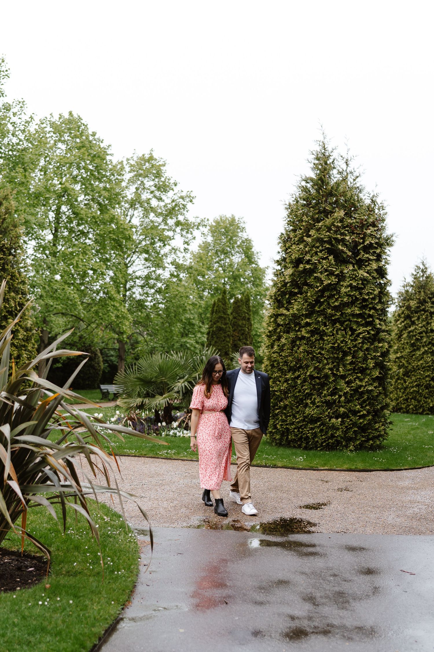 Relaxed couple taking a casual walk through Regents park among the greenery during their london engagement shoot