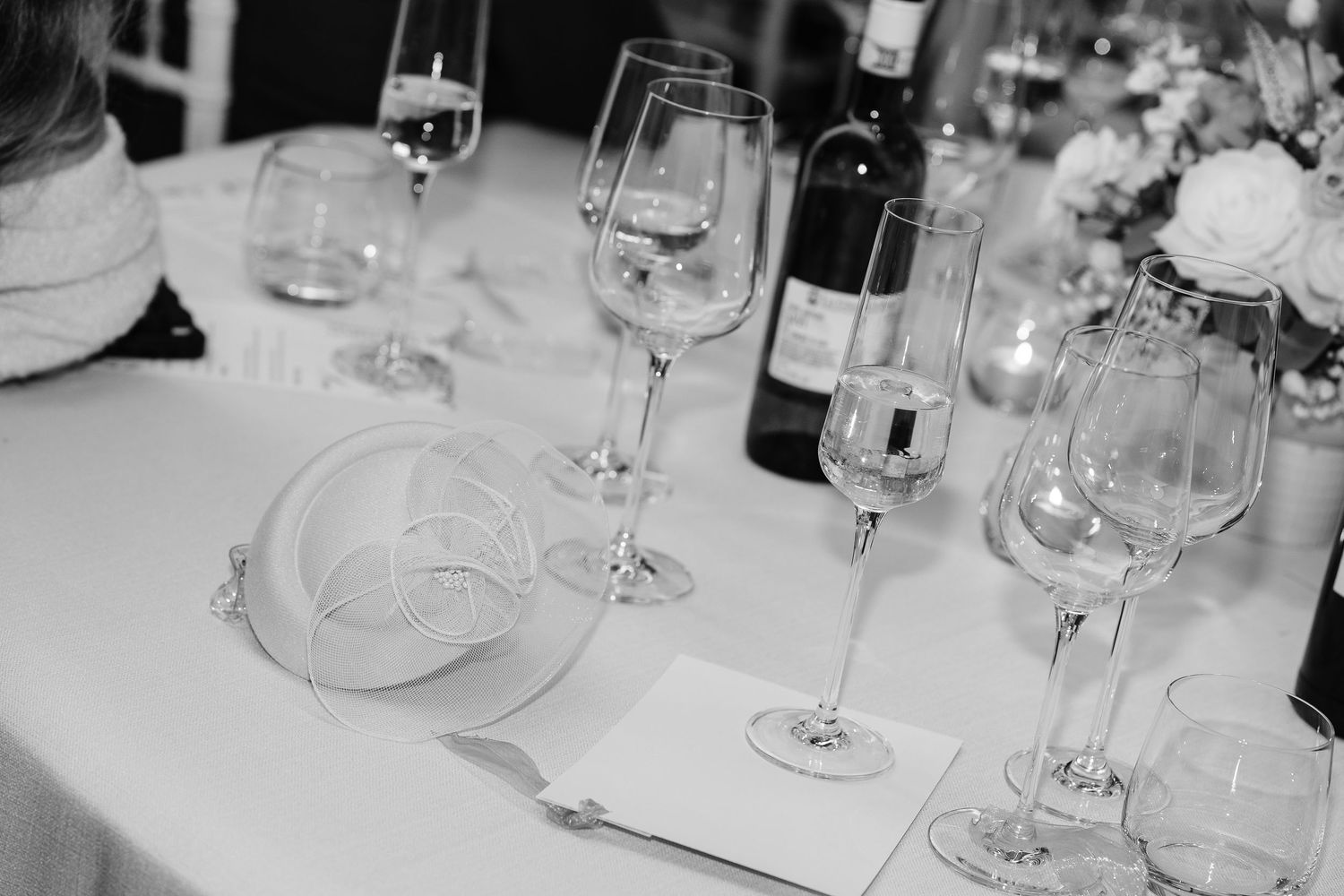 Elegant black and white wedding table setting with crystal wine glasses, white plates, and wine bottles.