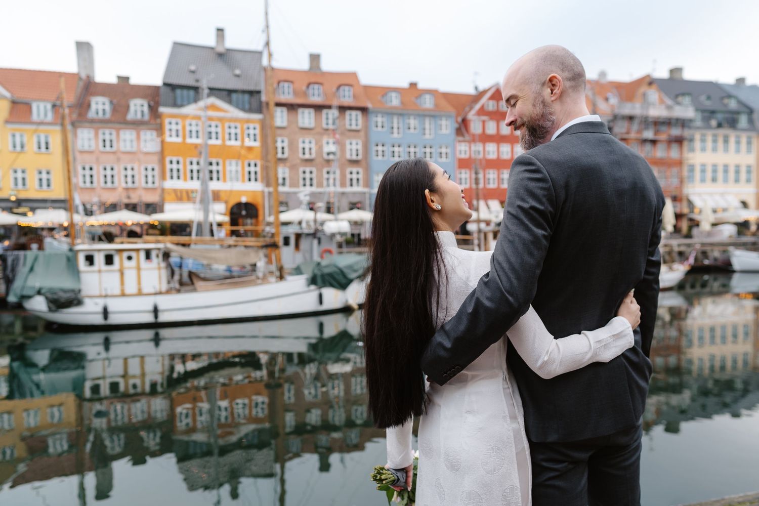 Bride and Groom having a cuddle on the canal of Nyhavn in Copenhagen for their couples portraits