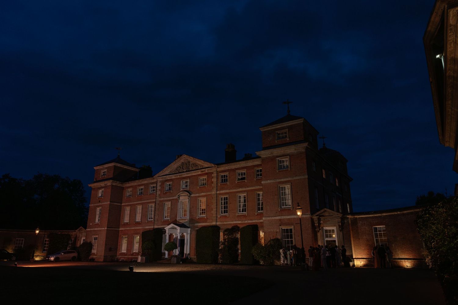 A stunning Georgian manor house illuminated at night during a wedding celebration.