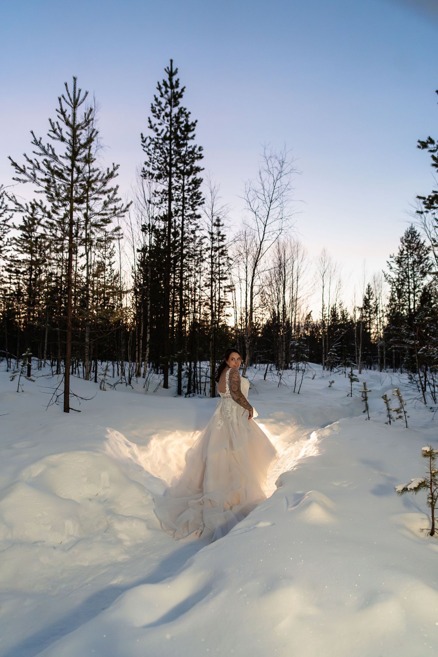 Couple candidly walking through forest at Twilight hour. Luxury Lapland wedding photographer. Snow wedding. Lapland wedding photos.