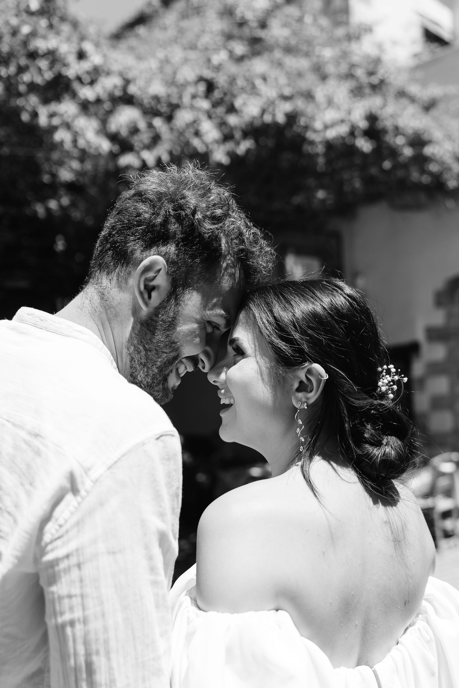 Black and white photo of bride and groom sharing an intimate forehead-to-forehead moment outdoors.
