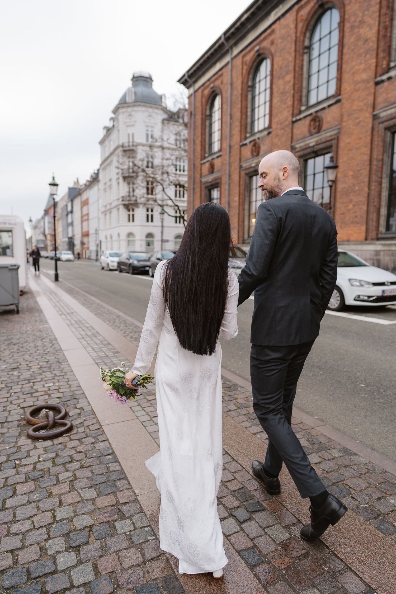 Newlyweds walking along Nyhavn Canal in Copenhagen. Denmark wedding. Scandinavian & Destination Wedding Photographer
