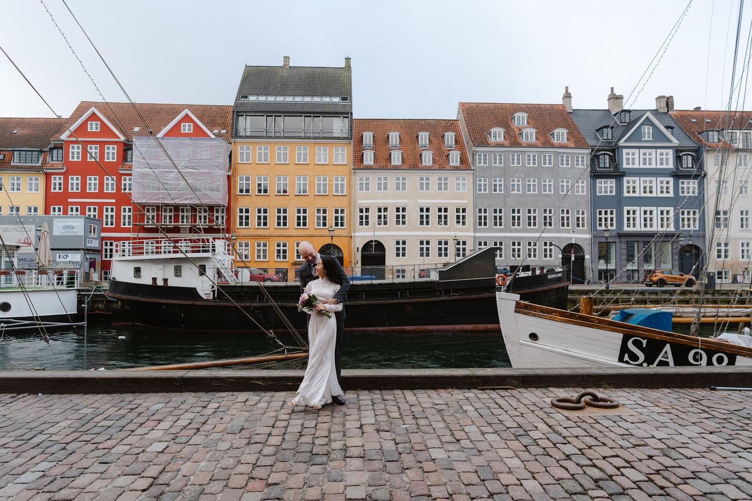 Newlyweds walking along Nyhavn Canal in Copenhagen. Denmark wedding. Scandinavian & Destination Wedding Photographer