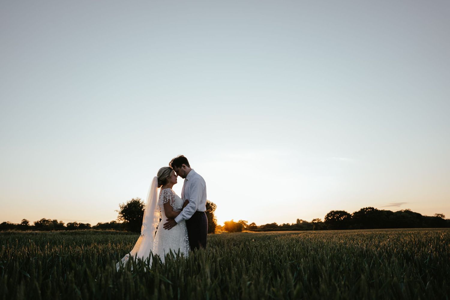 bride and groom facing each other in a beautiful norfolk field at golden hour sunset. norfolk wedding photographer
