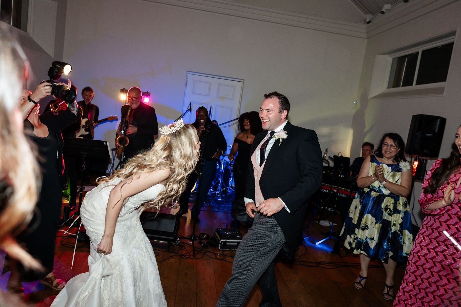 Bride and groom dancing passionately at wedding reception with live band performing on stage.