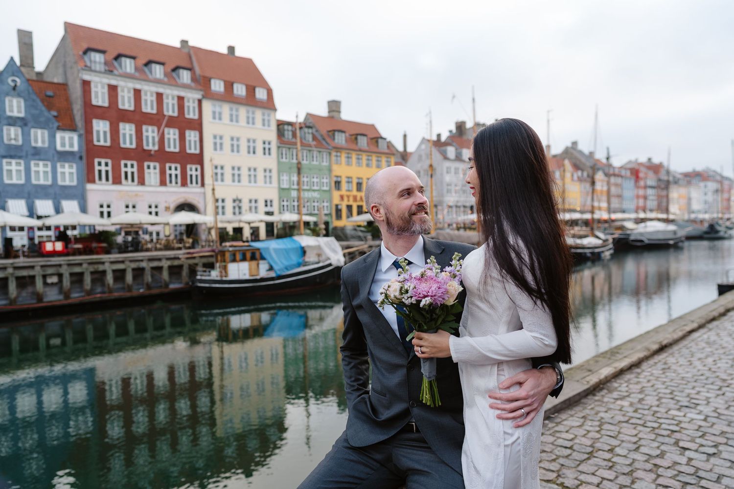 Newlyweds walking along Nyhavn Canal in Copenhagen. Denmark wedding. Scandinavian & Destination Wedding Photographer