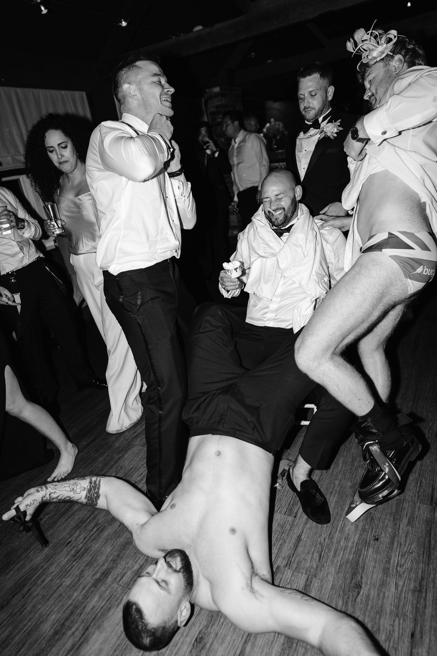 Wedding guests dance wildly on the dance floor in a fun black and white reception photo.