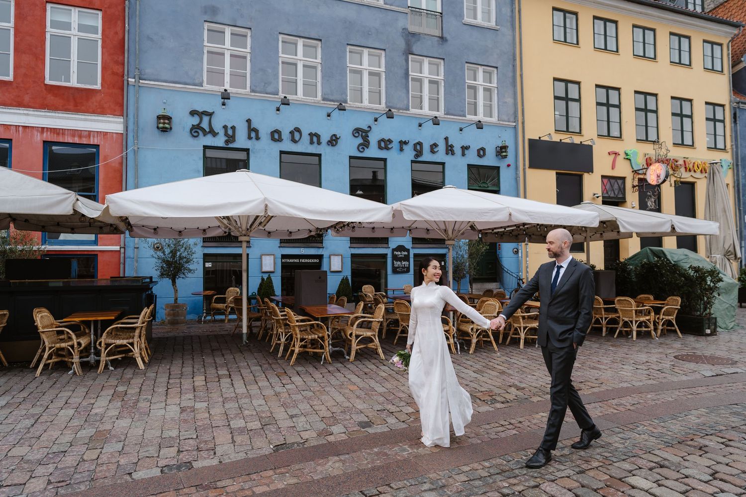 Newlyweds walking along Nyhavn Canal in Copenhagen. Denmark wedding. Scandinavian & Destination Wedding Photographer