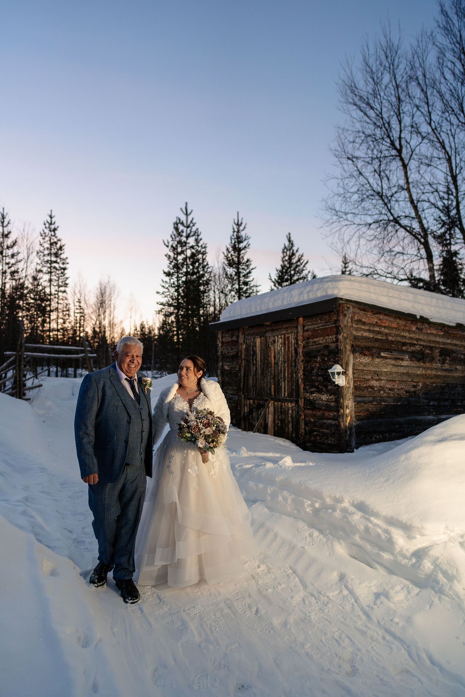 Couple smiling in snow at Twilight hour. Luxury Lapland wedding photographer. Snow wedding. Lapland wedding photos. Log cabin lapland.