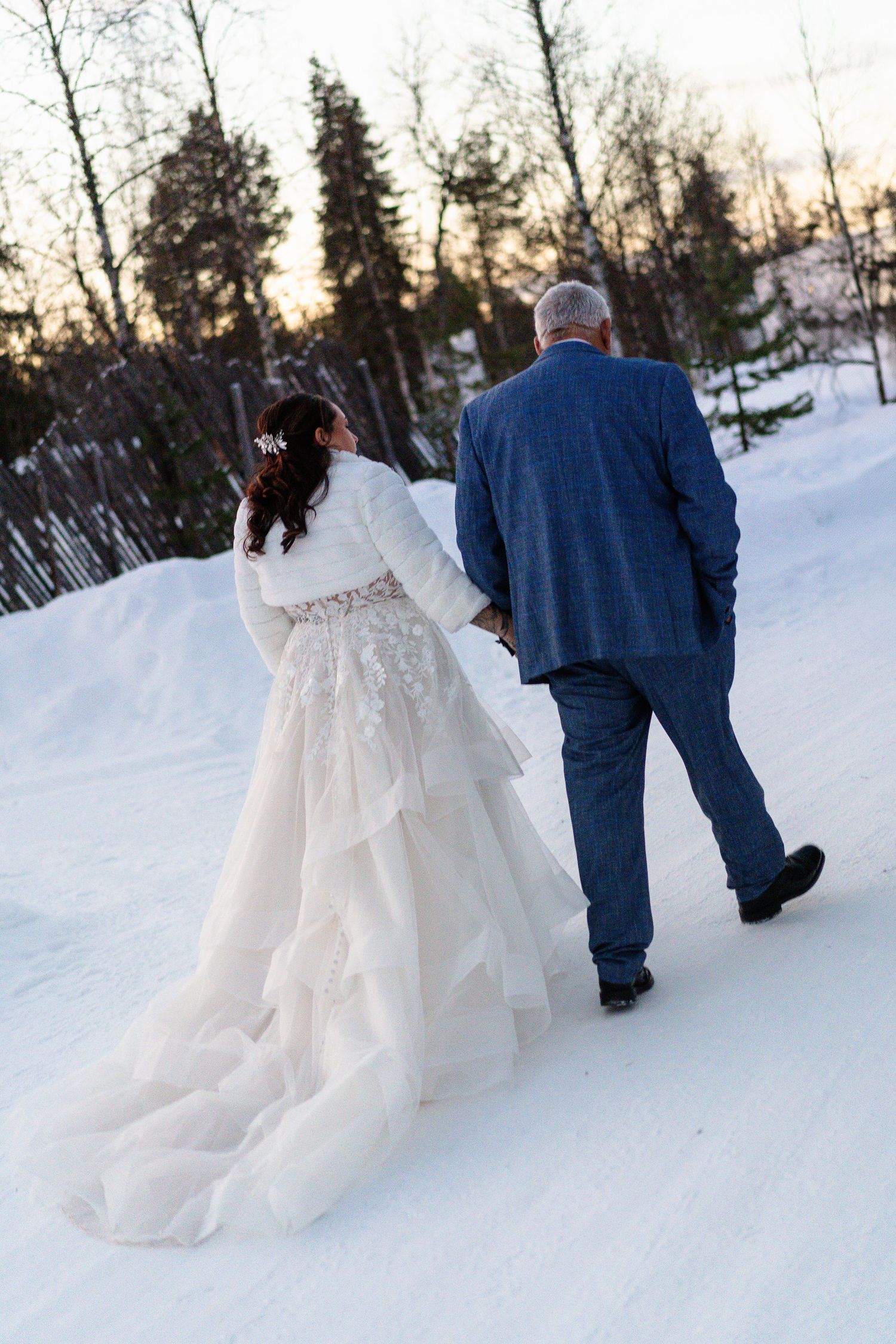 Couple candidly walking through forest at Twilight hour. Luxury Lapland wedding photographer. Snow wedding. Mountain Wedding.