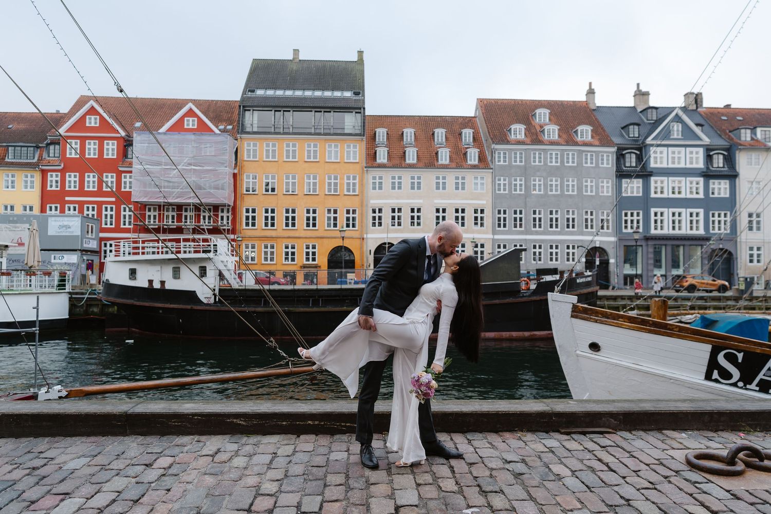 Newlyweds walking along Nyhavn Canal in Copenhagen. Denmark wedding. Scandinavian & Destination Wedding Photographer