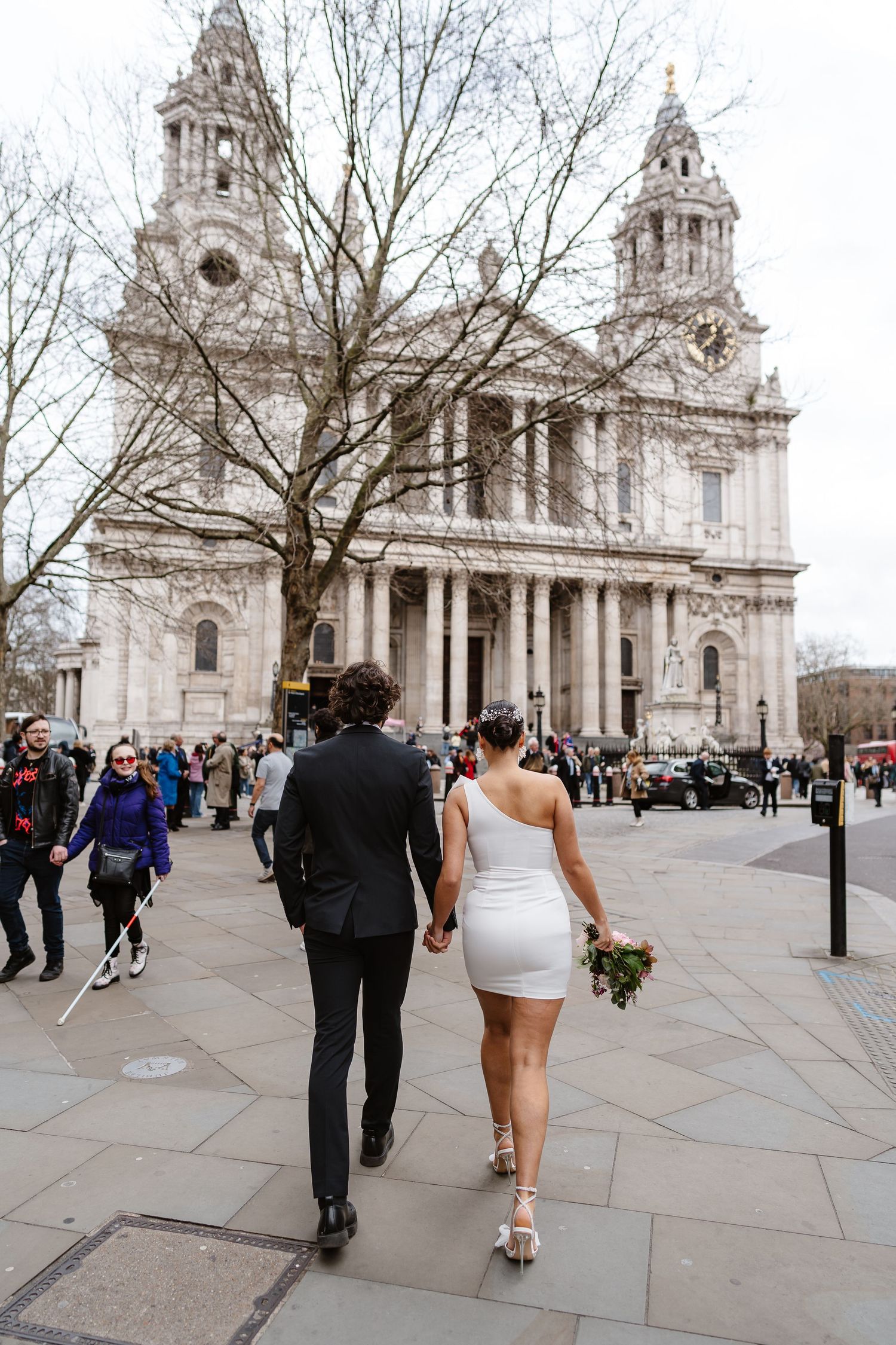 Luxury Bride & Groom walking past St Paul's Cathedral in London on wedding elopement. Wedding photographer