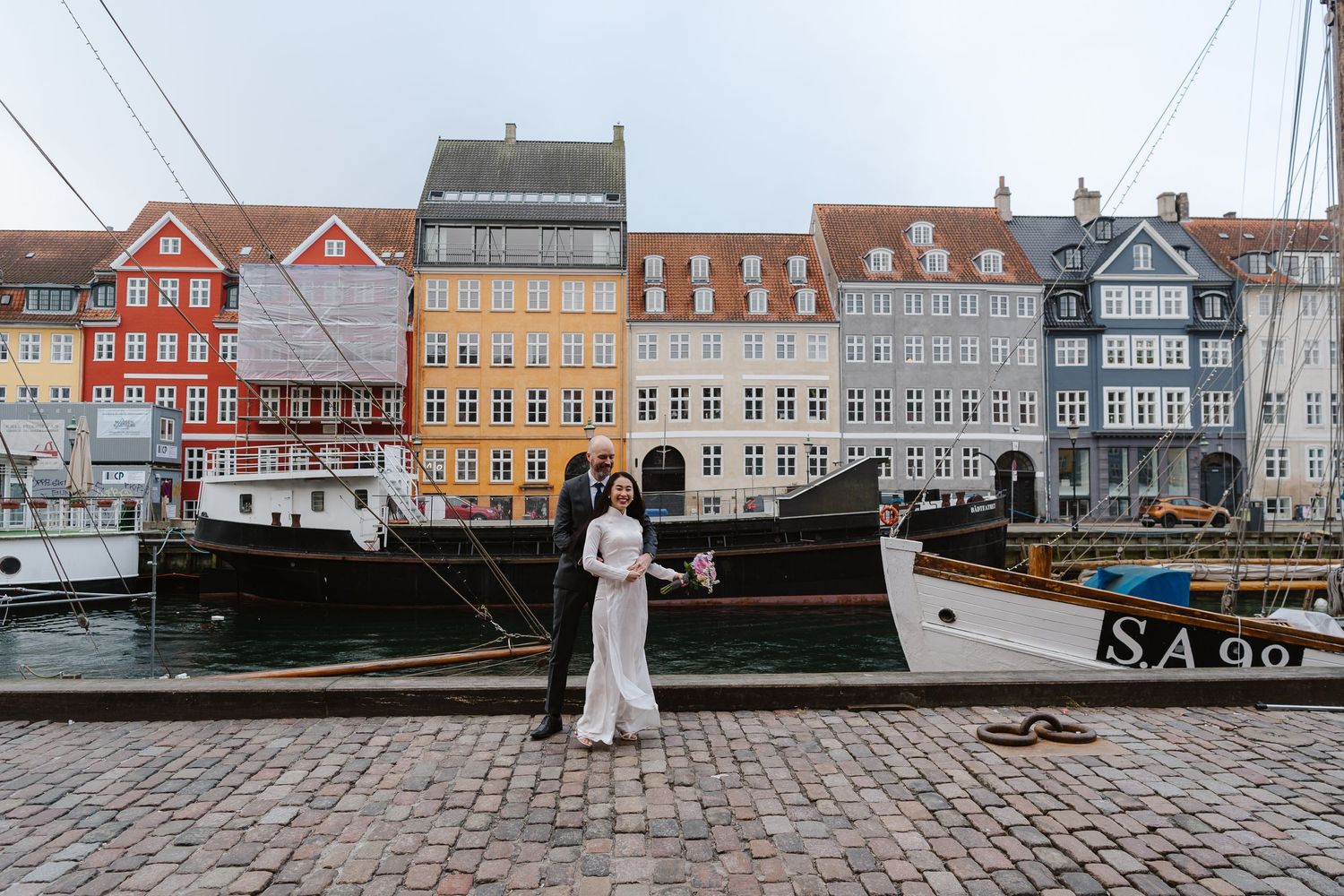 Newlyweds walking along Nyhavn Canal in Copenhagen. Denmark wedding. Scandinavian & Destination Wedding Photographer