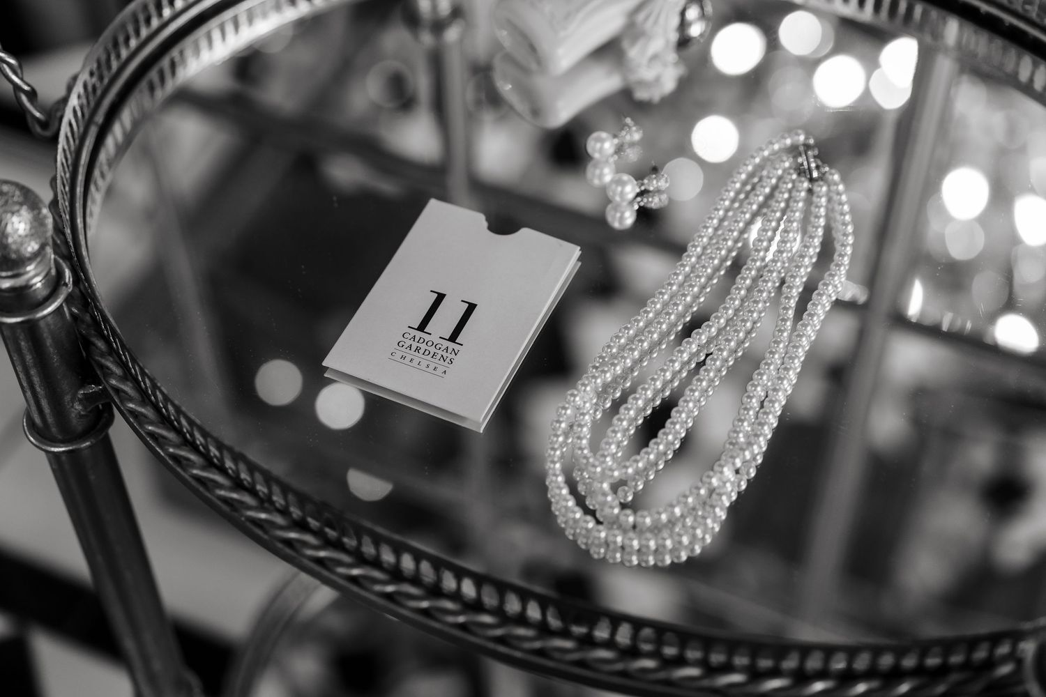 A black and white image of pearl necklaces and a card on a glass vanity tray.