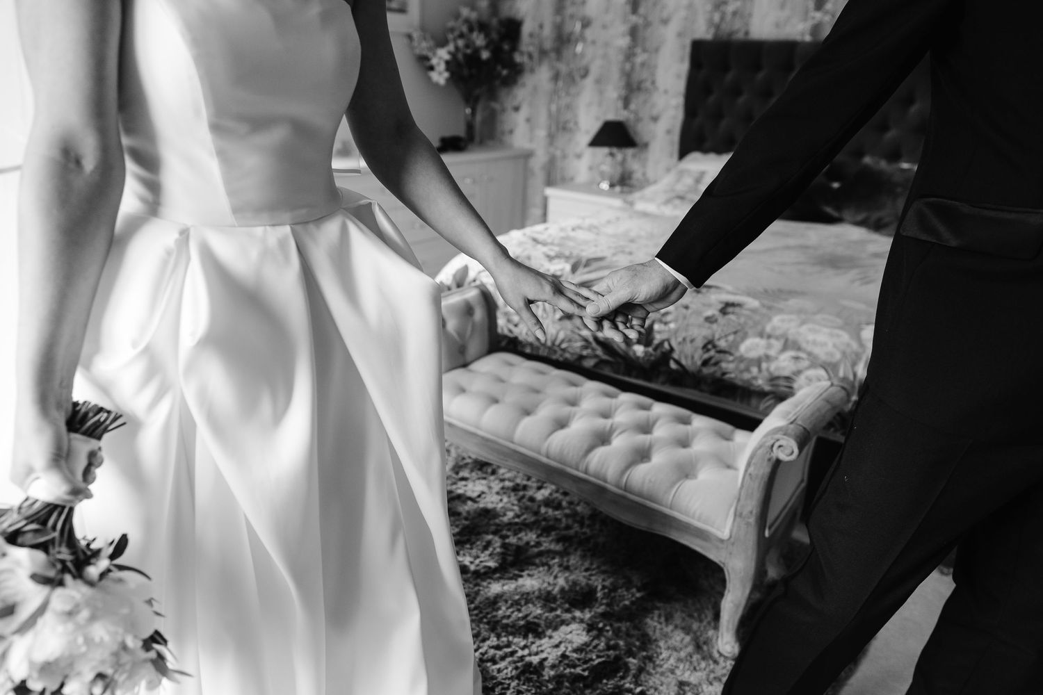 Black and white photo of bride and groom holding hands at their wedding ceremony.