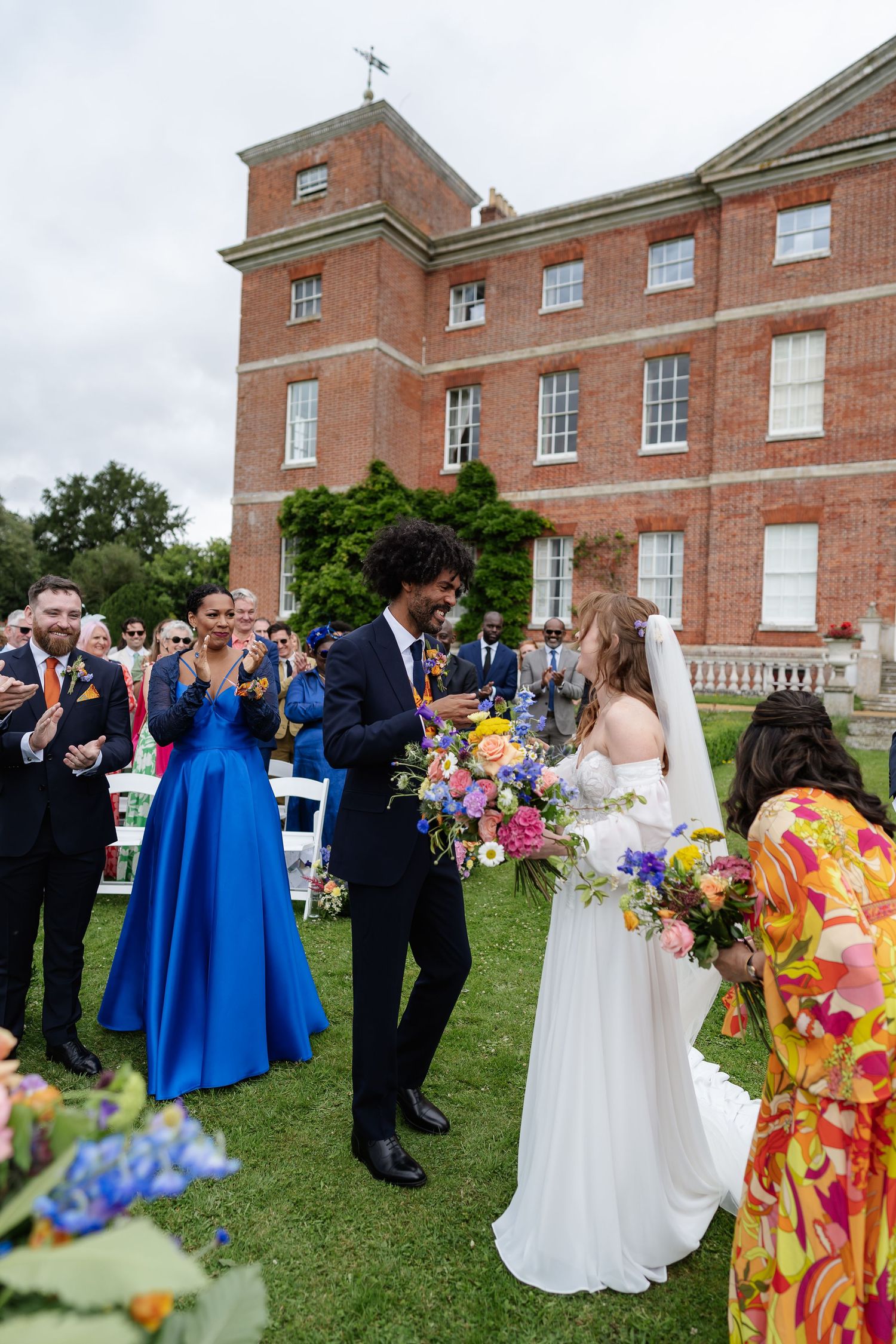Bride and groom walking down aisle at outdoor wedding ceremony with guests applauding at brick manor.