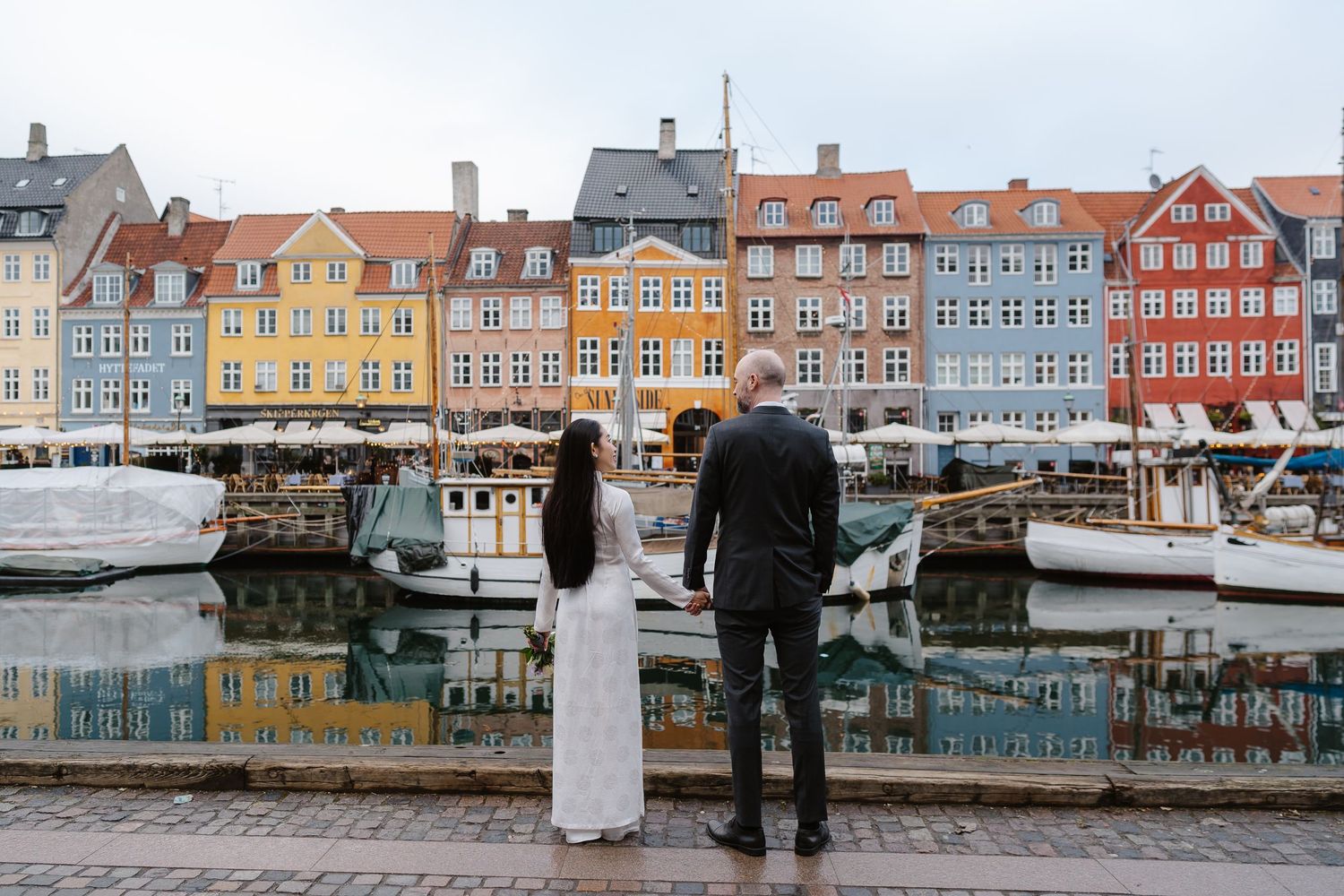 Newlyweds walking along Nyhavn Canal in Copenhagen. Denmark wedding. Scandinavian & Destination Wedding Photographer